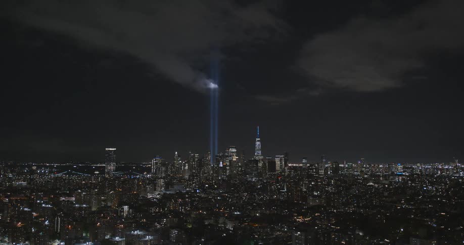Pillars of light extend into the sky over the downtown of a metropolis at night
