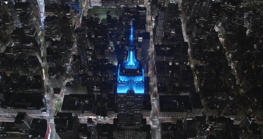 The empire state building is lit blue at night