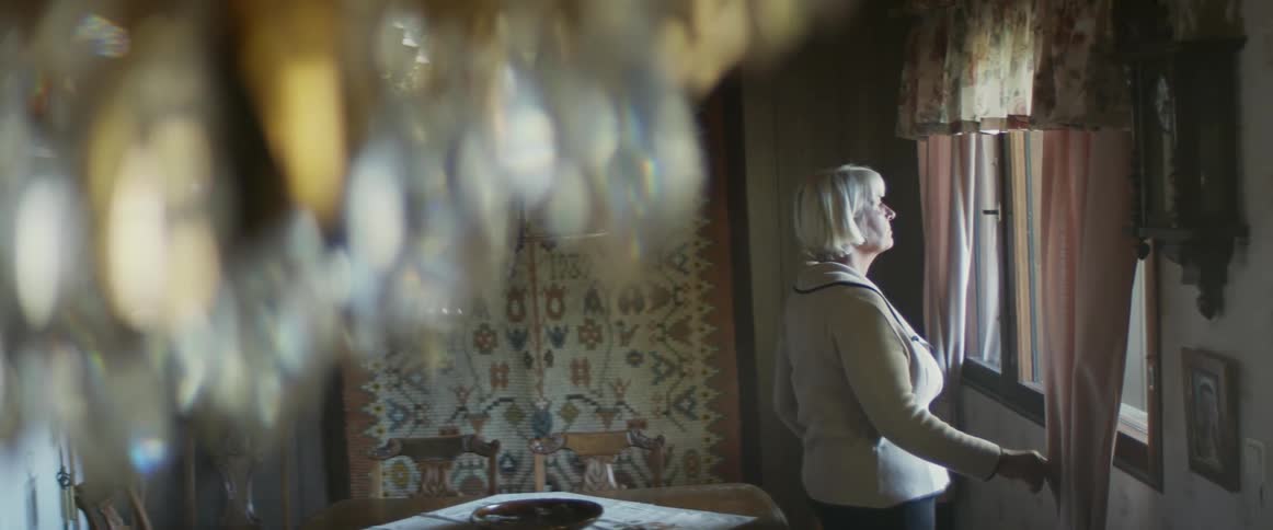 A woman is looking out a window at night