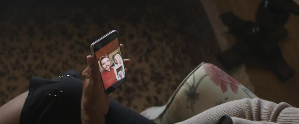 Elderly woman sitting in an armchair makes a video call on a smartphone