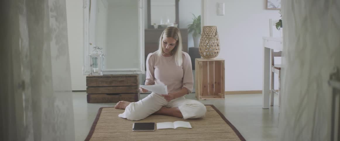 Woman sitting on the floor of the living room working from home