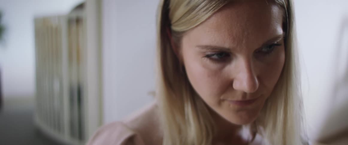 Blonde woman with a pink sweater looks down and uses a tablet