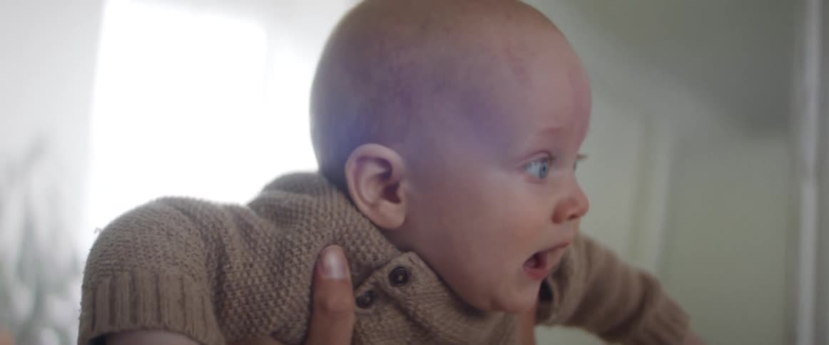 A mother laughs as she lifts her baby up in to the air