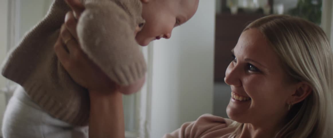 A woman holds her baby in the air and then pulls him in for a hug