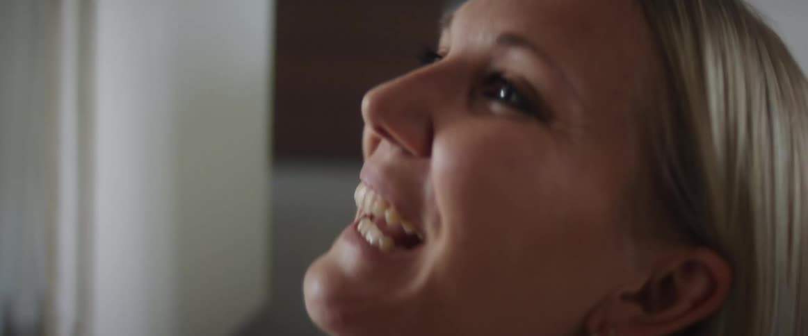 A woman at home laughs and talks to her baby as she picks him up