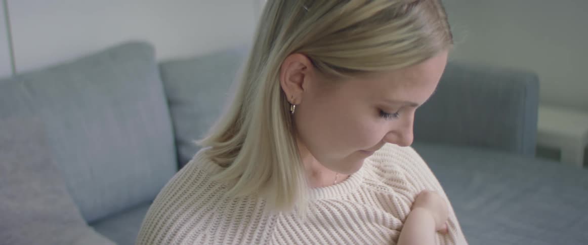 Mother breastfeeding infant on sofa