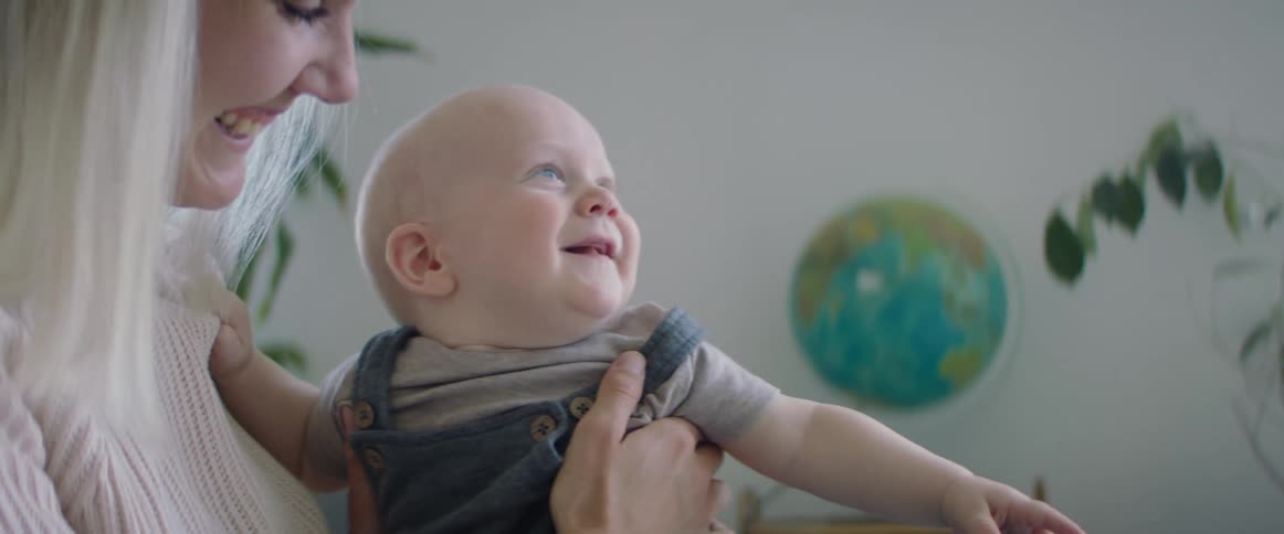 Mother holds baby boy lovingly in her hands at home while smiling