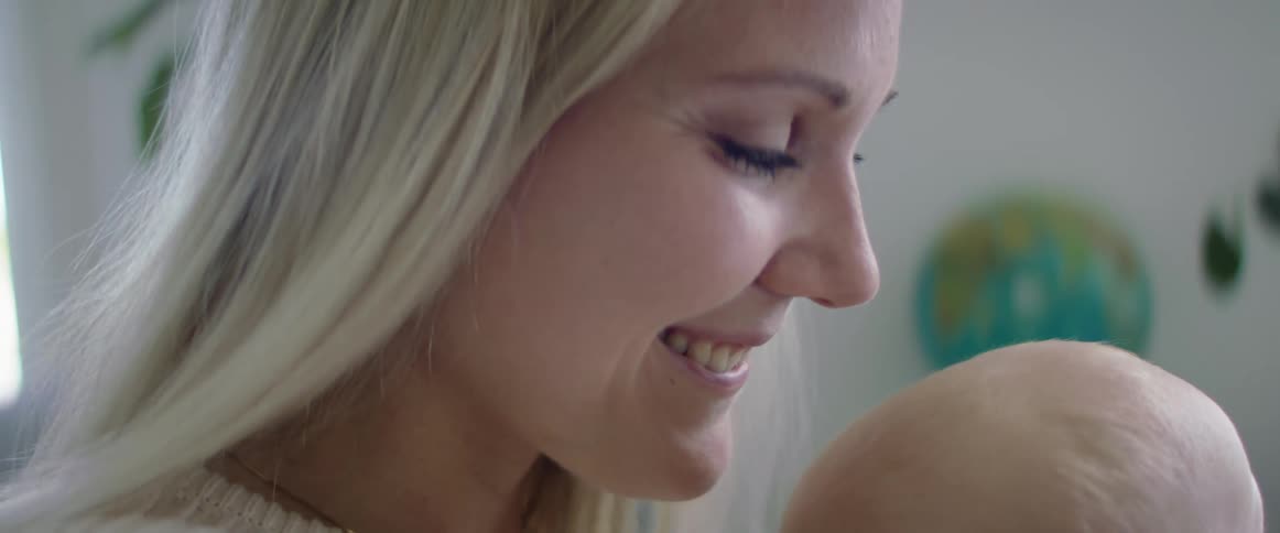 Mother holds her baby smiling while sitting in the couch on the living room