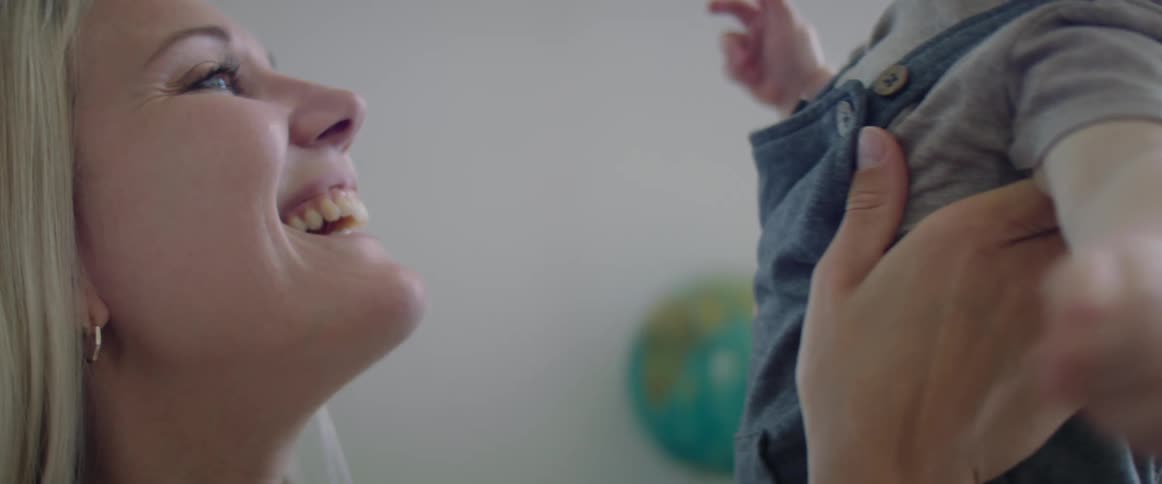 Mother playfuly holds baby in her hands in the living room at home
