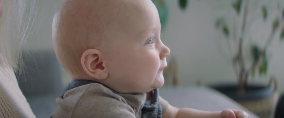 Mother holds smiling child in living room as she also smiles