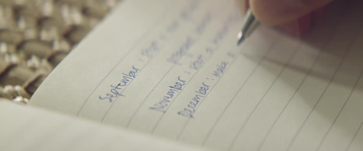 Person writing in journal with ballpoint pen