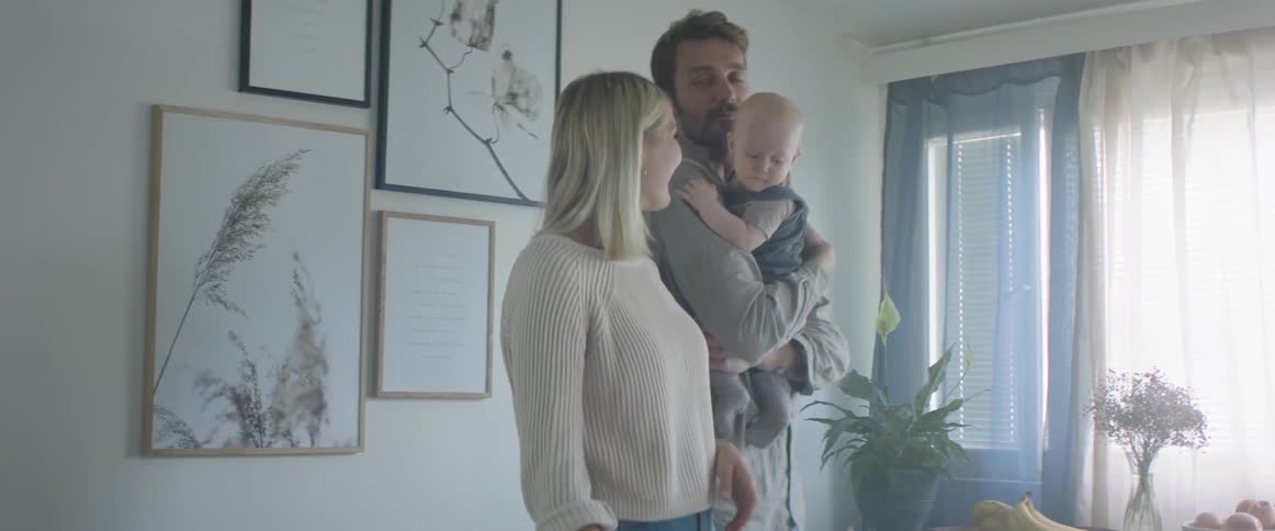 A man brings his baby into the kitchen to see his wife