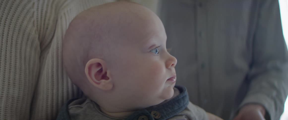 Parents holding baby boy wearing overalls