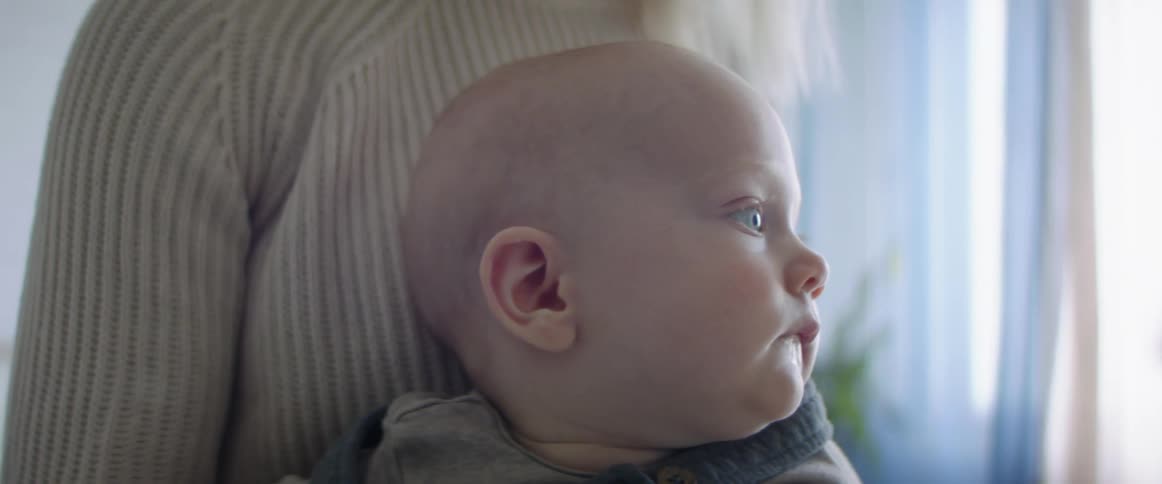 Blonde mother with a white knit sweater holds her baby son