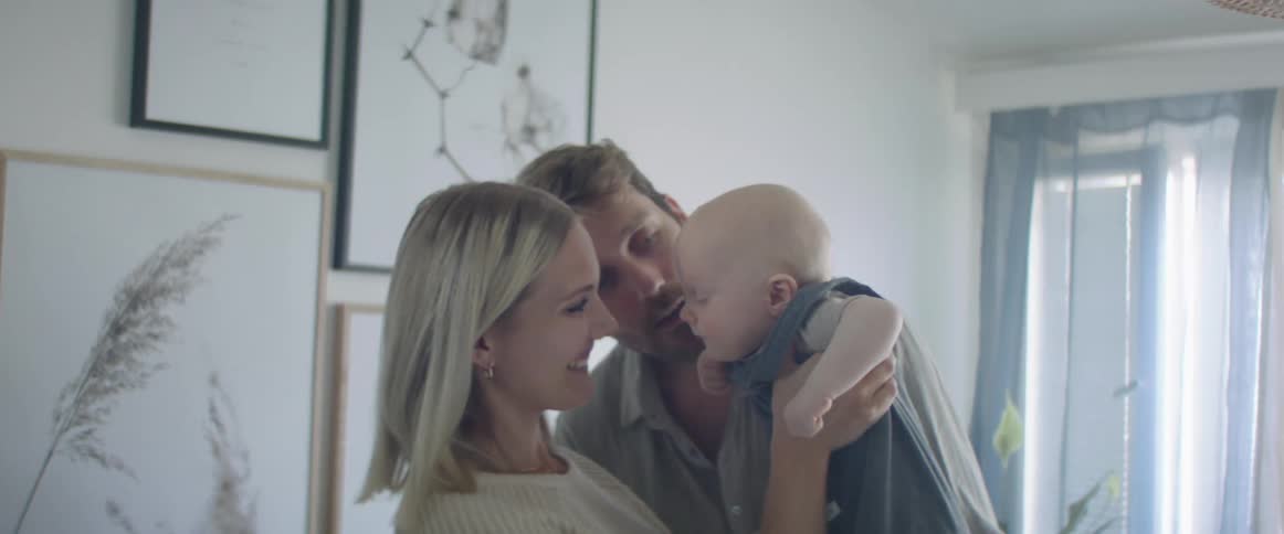 Young couple play with their baby in a room at home