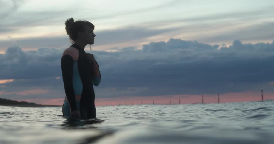 A woman standing in the water in a wet suit