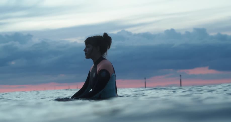 Woman wearing a swimsuit stands in the ocean as the waves move next to her