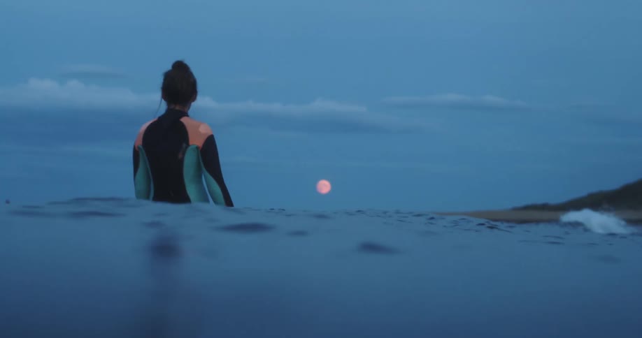A woman looking into the ocean to the moon