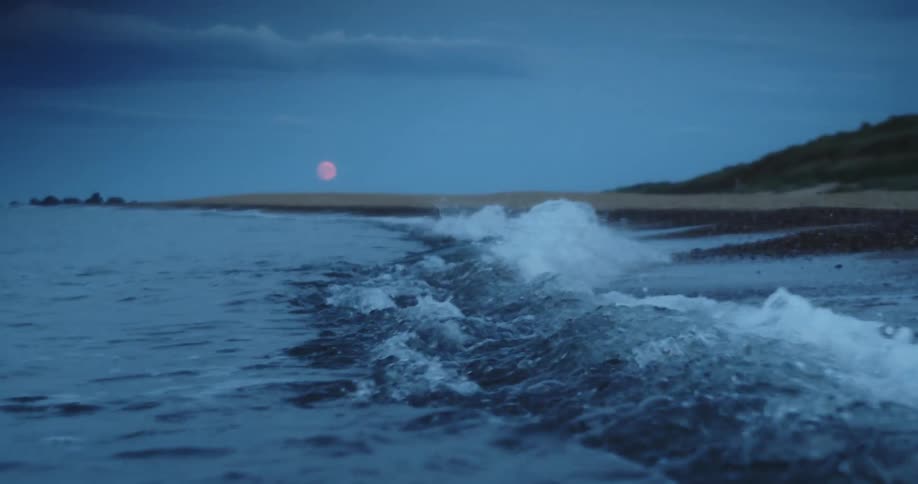 Waves rolling in on coastline with the moon on the horizon