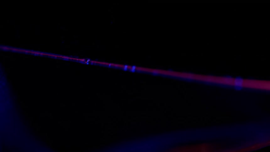 A red and blue line glows brighter and becomes sharper against a black background on a monitor