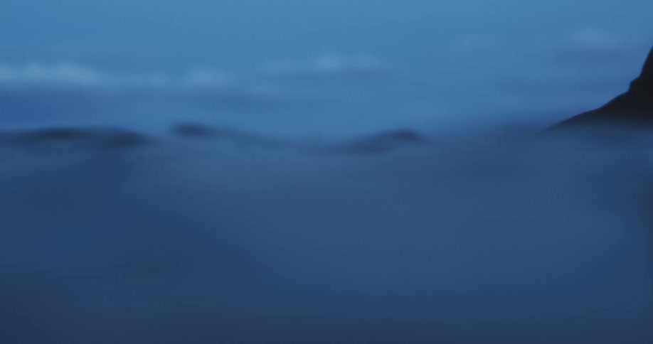 A scuba diver floats upright in the ocean and relaxes with his arms out and up