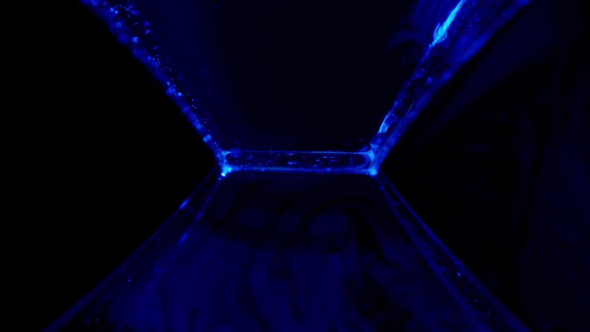 Abstract footage of bubbles passing through neon blue lights
