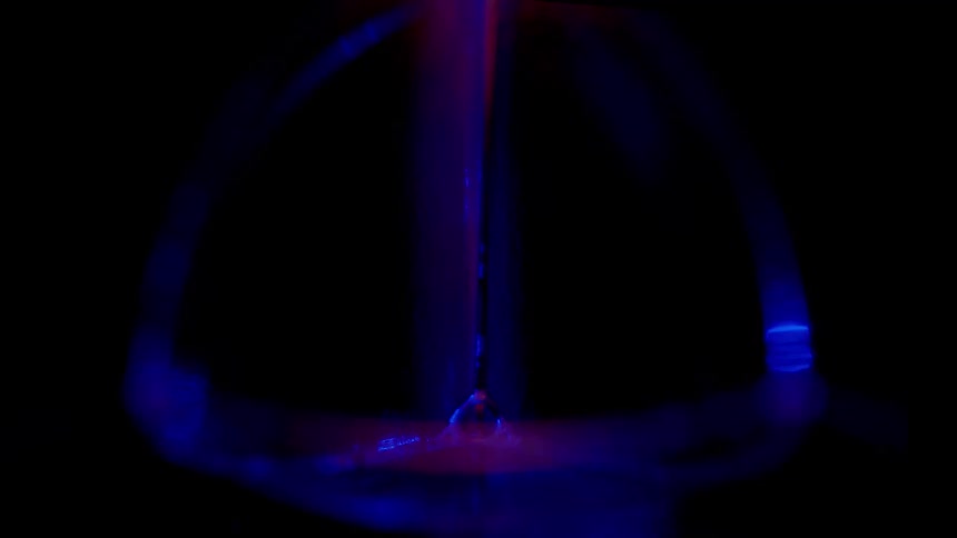A bubble is slightly illuminated with a blue light in a darkened space