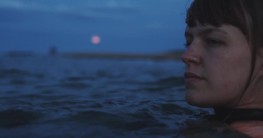 A woman is swimming at sunset