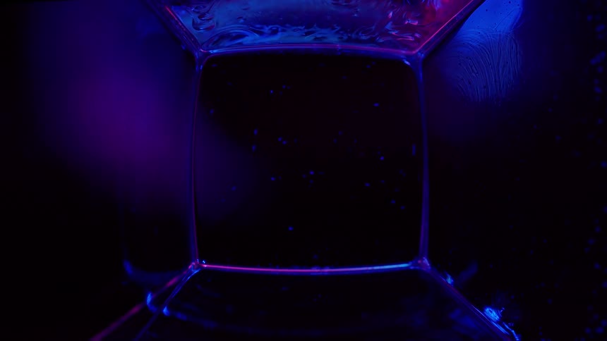Fluorescent fosforescent liquid inside a square container shines under ultra violet light
