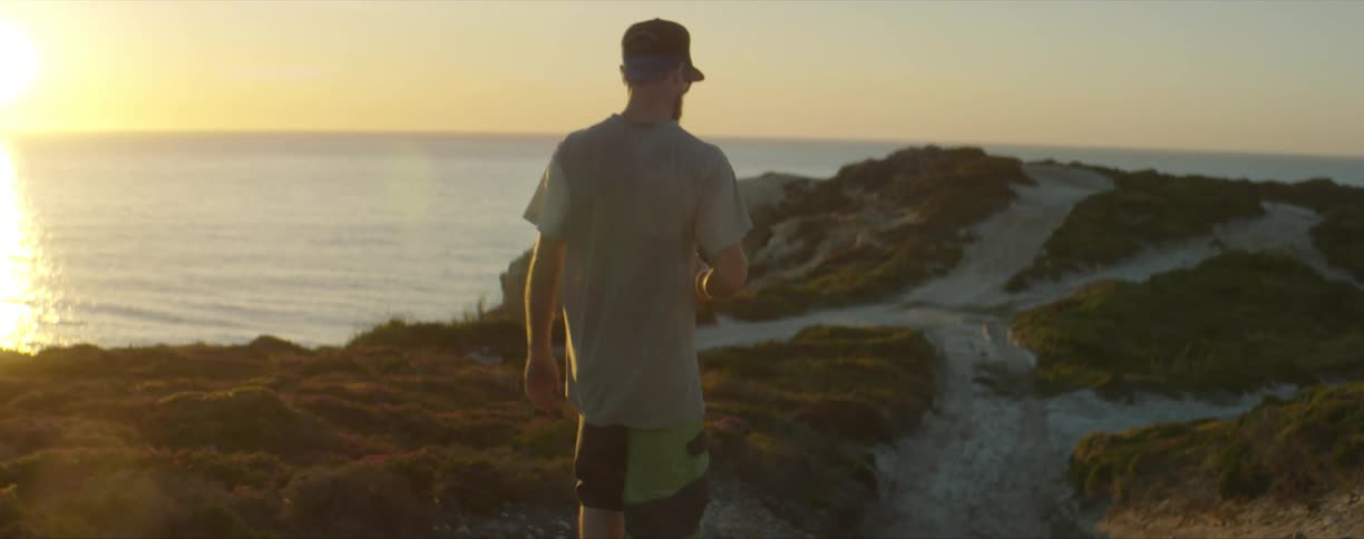 A man walks on a cliff on the shore