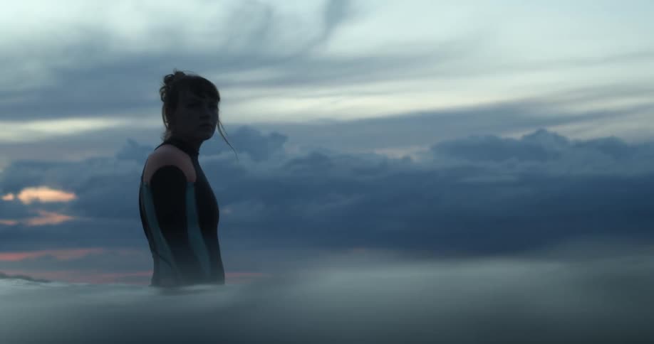 A woman standing in the ocean in a wet suit