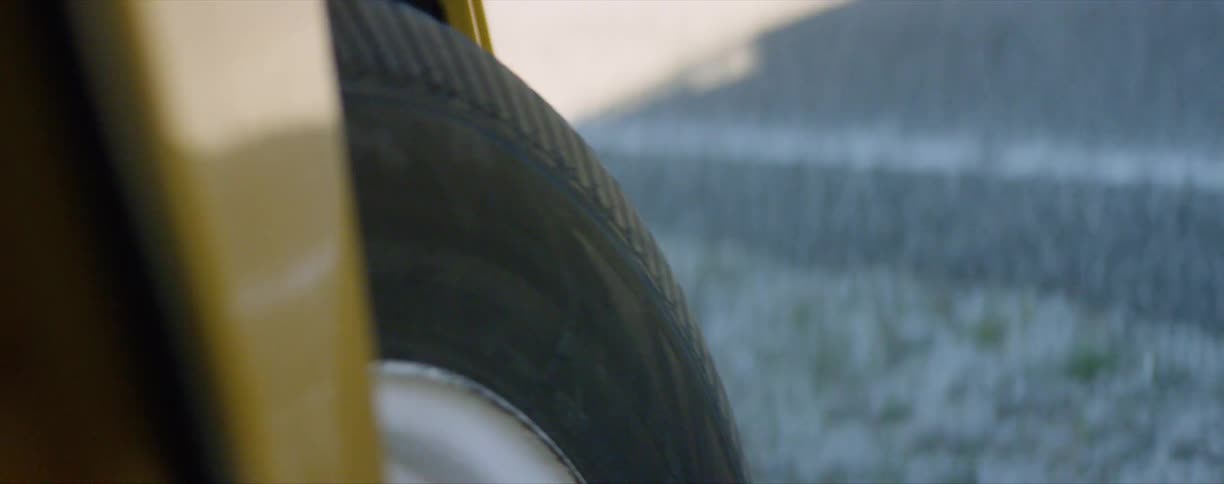Close up of the spinning tire of a bright yellow van drivin gover a road