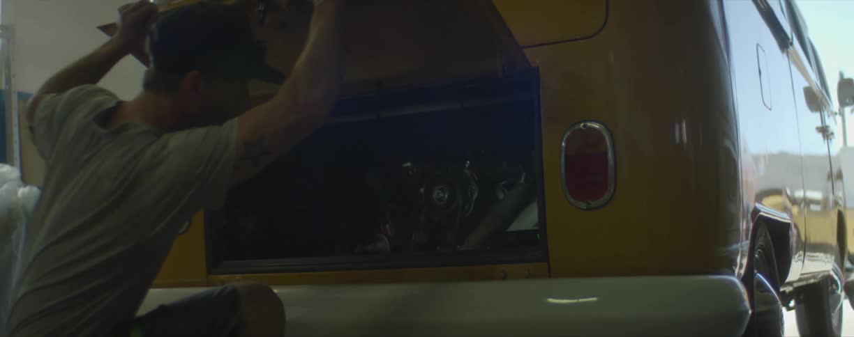 A man opens the back of a parked yellow van