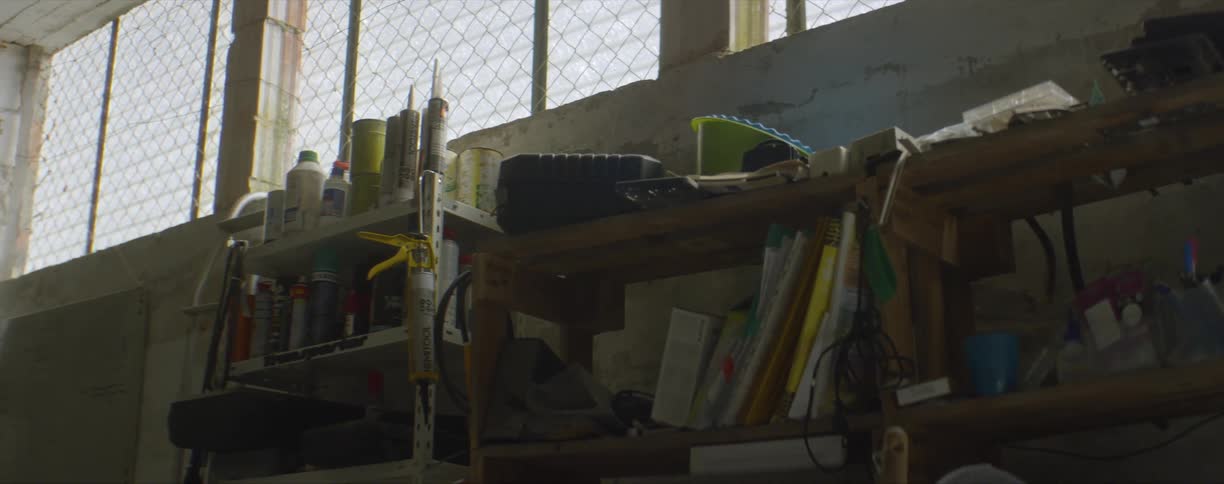 Shelfs on the wall of a dimly lit workshop filled with assorted items