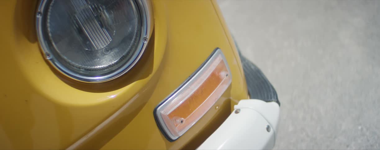 The front corner of a yellow vehicle parked on a road during the day