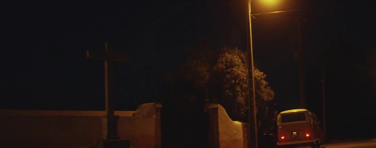 Bright yellow van parked under a streetlight in a rural area at night