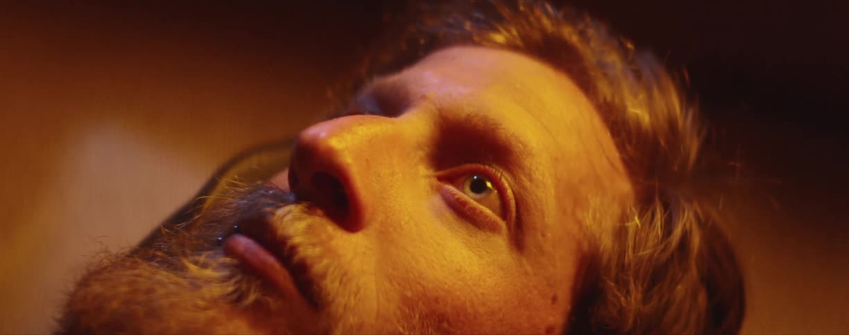A man lying down looking up as a light shines on him