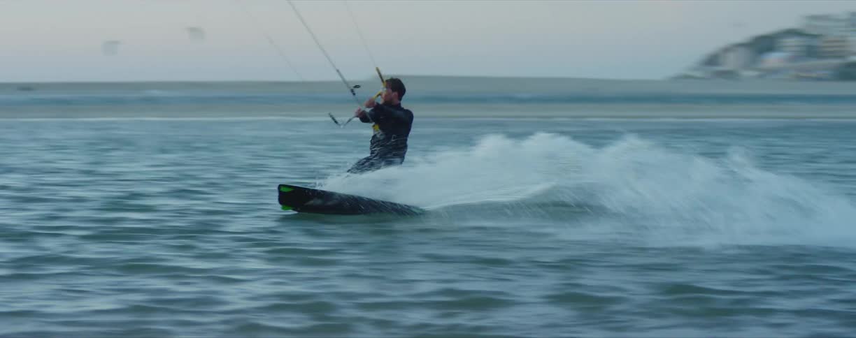 A man water skis with a skyline in the distance