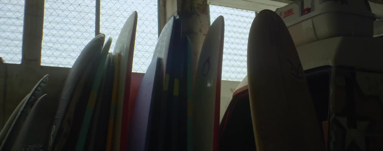 A group of surfboards stacked up together in a storage building