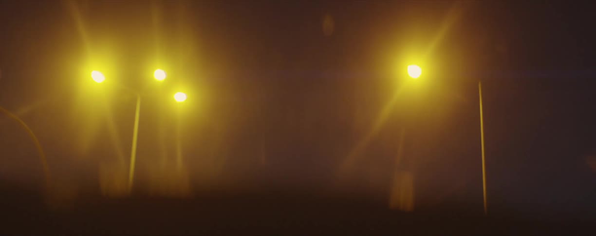 Traffic lights blinking yellow at nighttime viewed from the inside of a moving vehicle