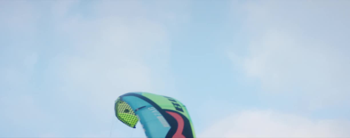 A kite with strings floating in the wind with the sky and clouds in the background