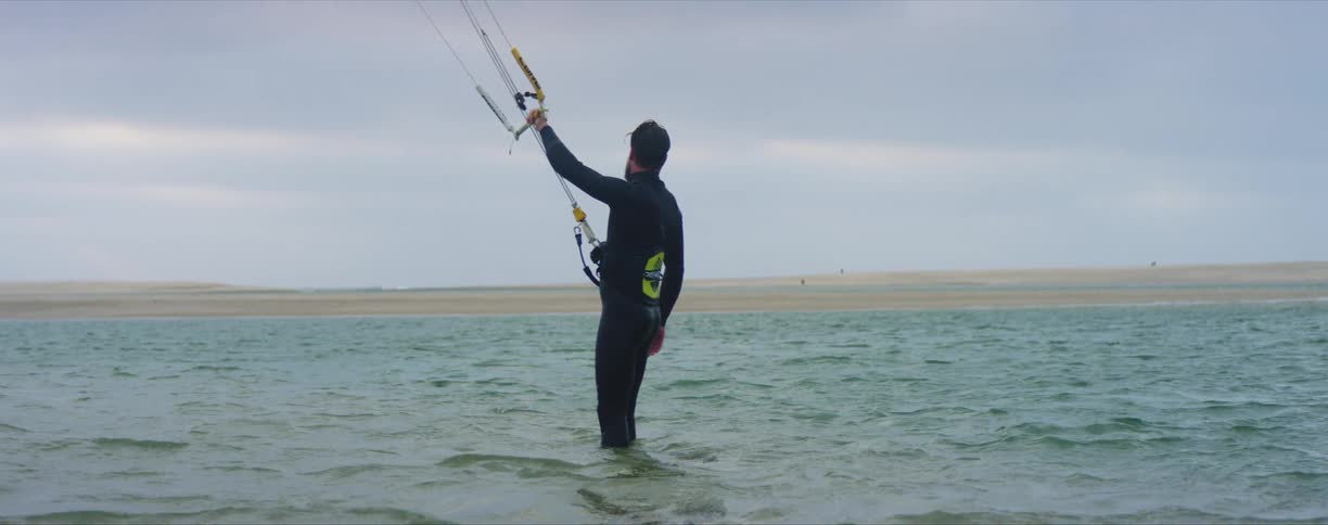 A man stands in the water holding on to a rope as he waits to be pulled in the water