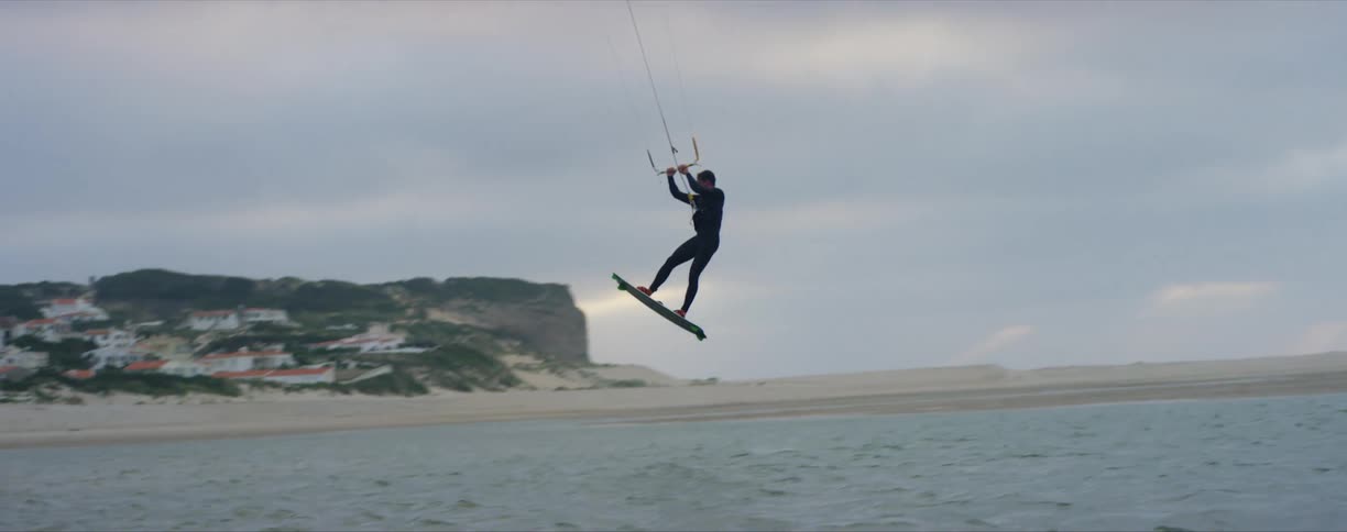 Surf glider lands on ocean near town nestled against promontory