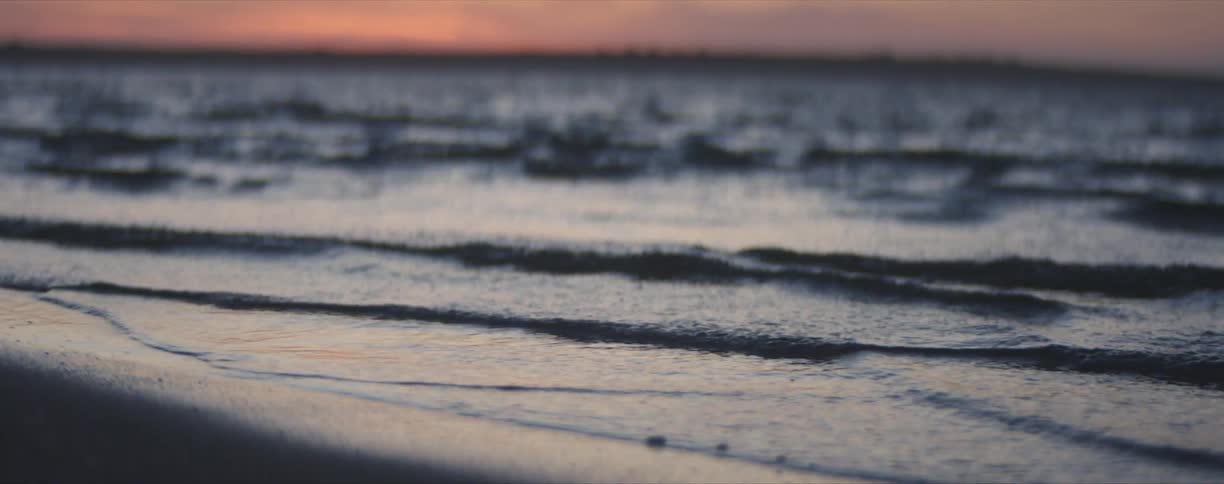 Waves rolling in on beach and a pink sky