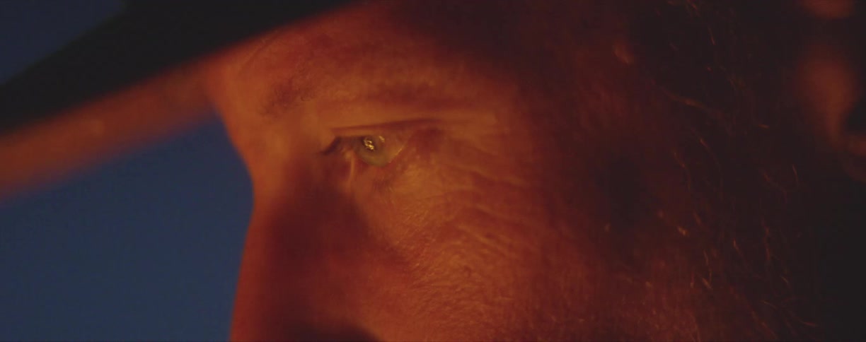 Close up of a mans face as he sits around a burning fire