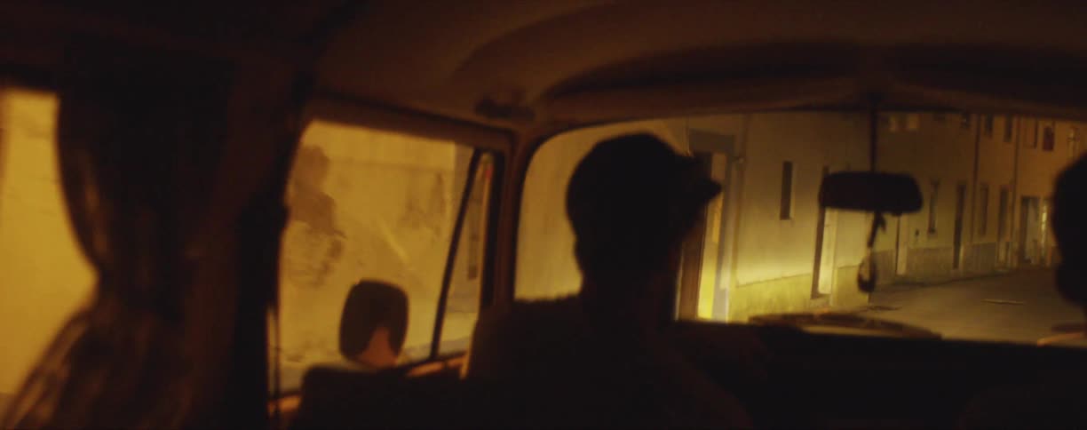 Man driving a van on a narrow alley in a town at night