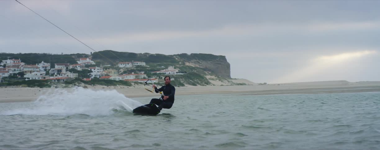 A man holds on tight as hes pulled by an aircraft while wind surfing