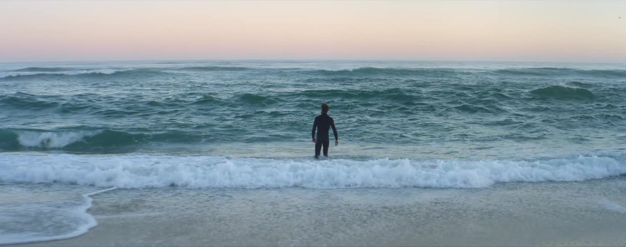 A man in a wetsuit walking into water