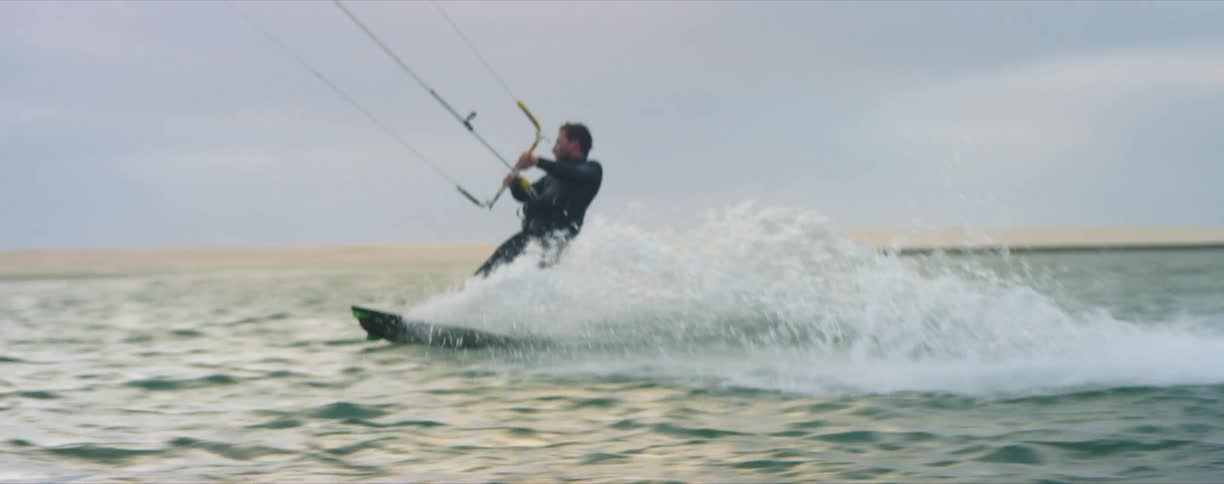 Man kite surfing near the coast on the ocean at sunset