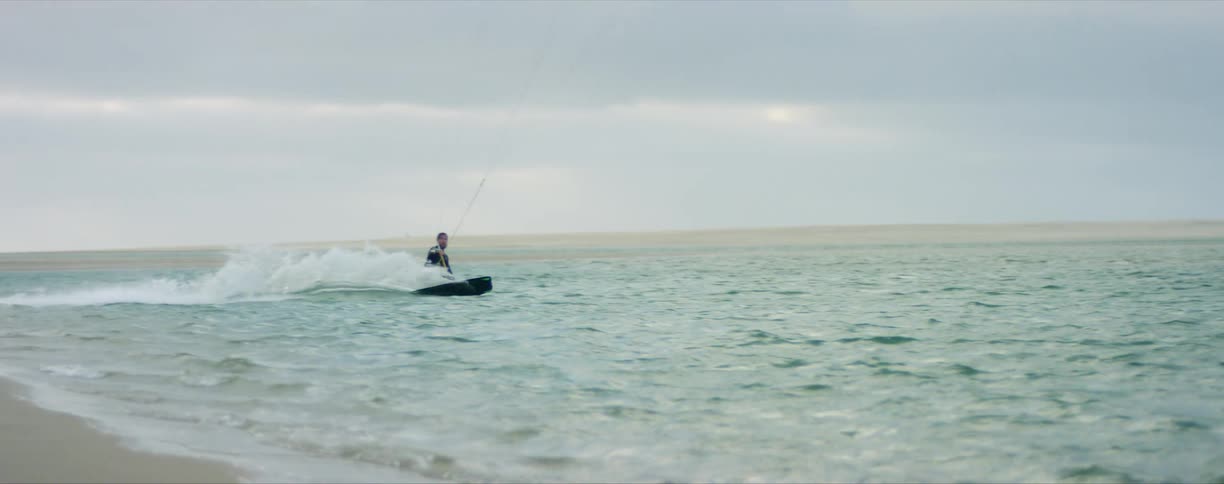 Man kite surfing in the ocean near the beach at evening